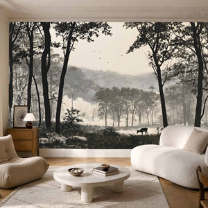 Papier peint forêt noir et blanc avec vallée boisée, biche, arbres élancés et reliefs lumineux
